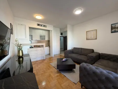 Living room with a sofa set and a view of the kitchen with a breakfast bar. - image 4