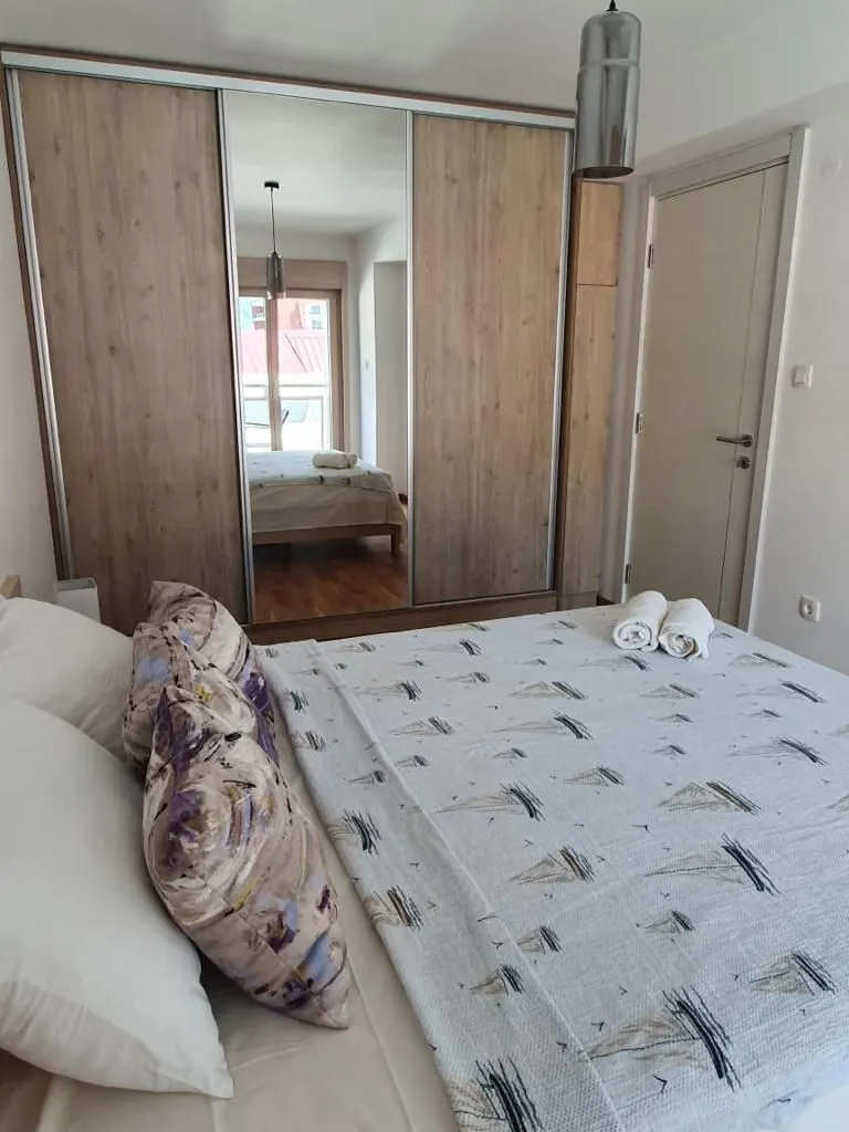 Furnished bedroom with a large double bed and a built-in wardrobe with a mirror.