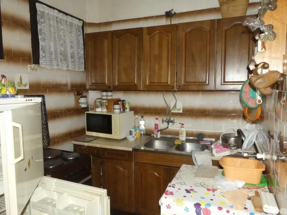 Older kitchen with wooden cabinets and a sink.