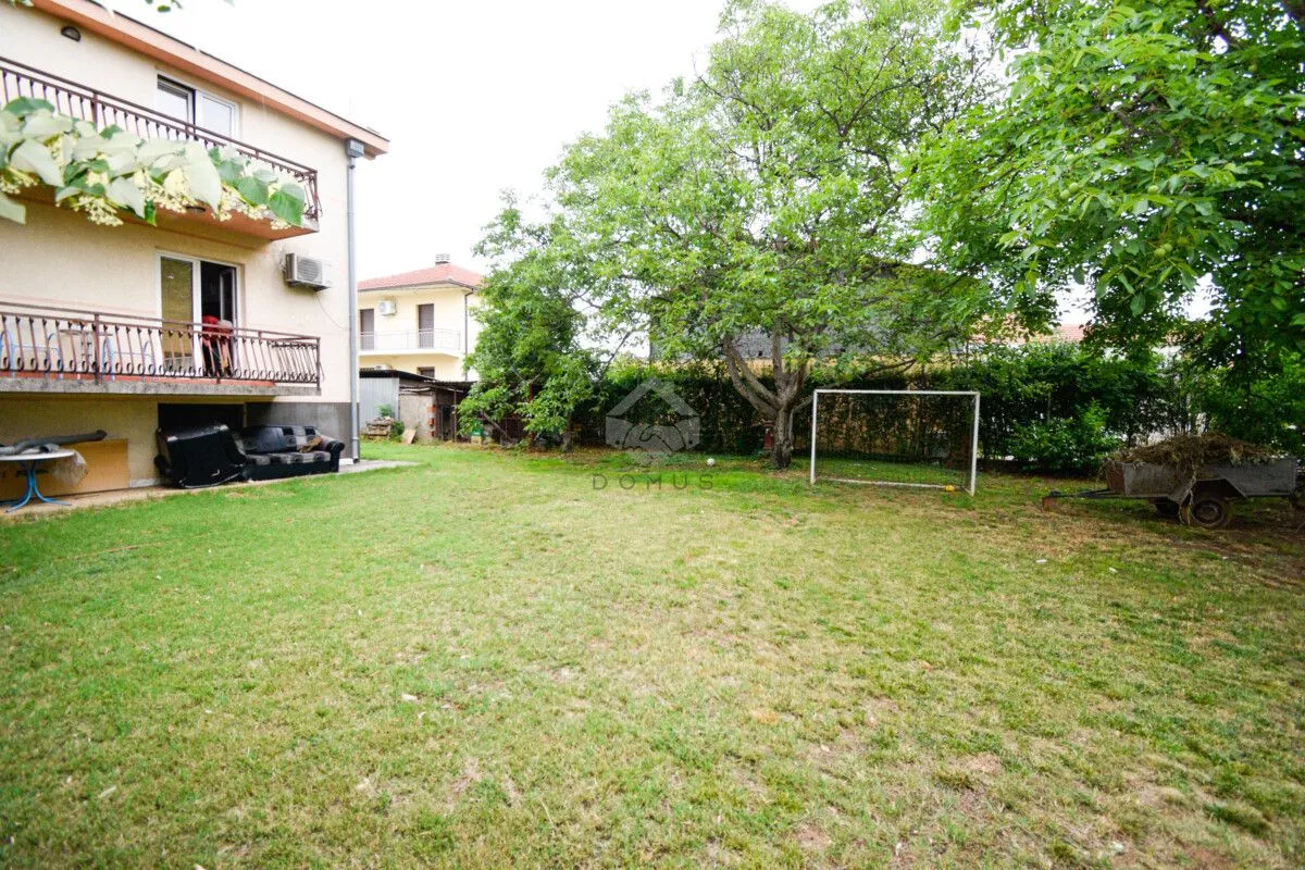 Spacious grassy yard with trees and a small football goal.