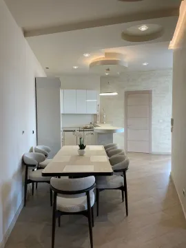Modern dining area with a table, chairs, and a kitchen in the background. - image 5