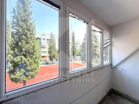 Zastakljeni balkonski prostor sa pogledom na igralište i drveće. - image 12