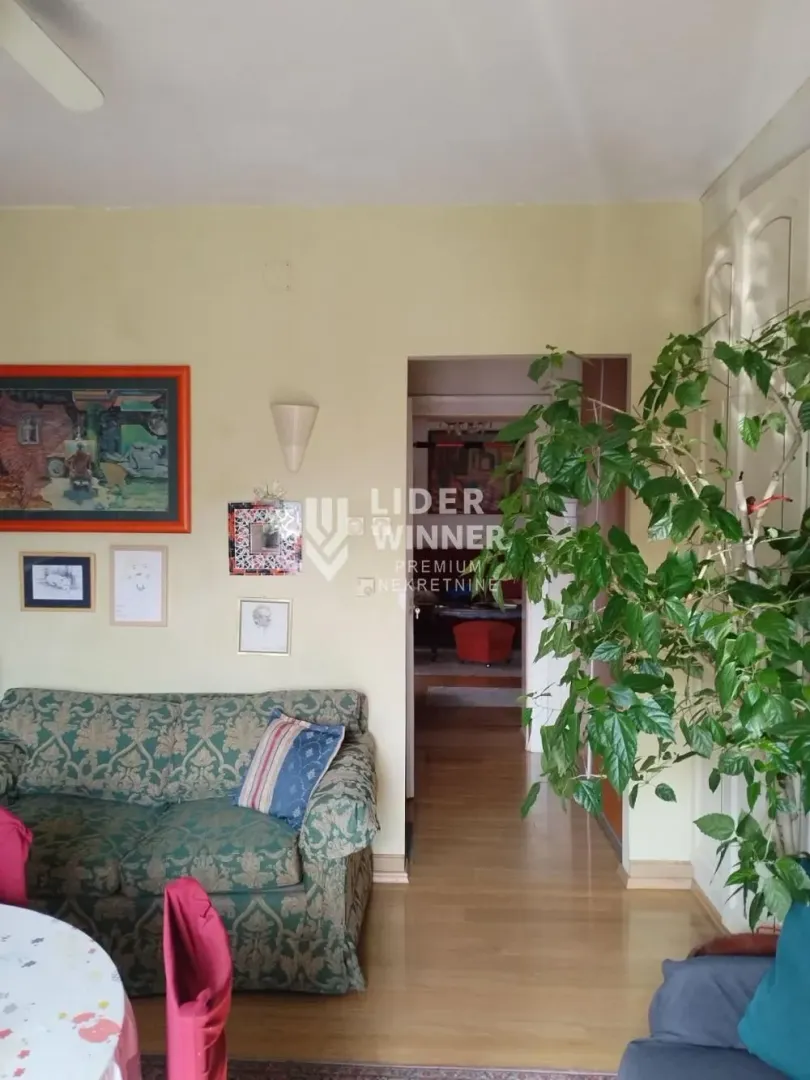 Dnevna soba sa garniturom za sedenje i umetničkim slikama na zidu.