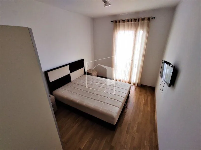 Spavaća soba sa bračnim krevetom, parketom i izlazom na terasu.