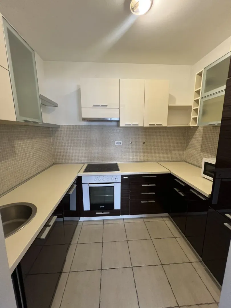 A modern kitchen with white upper cabinets and dark lower cabinets.
