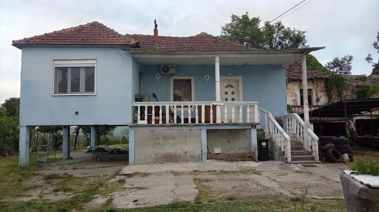 Pogled na spoljašnjost kuće sa terasom i stubovima.