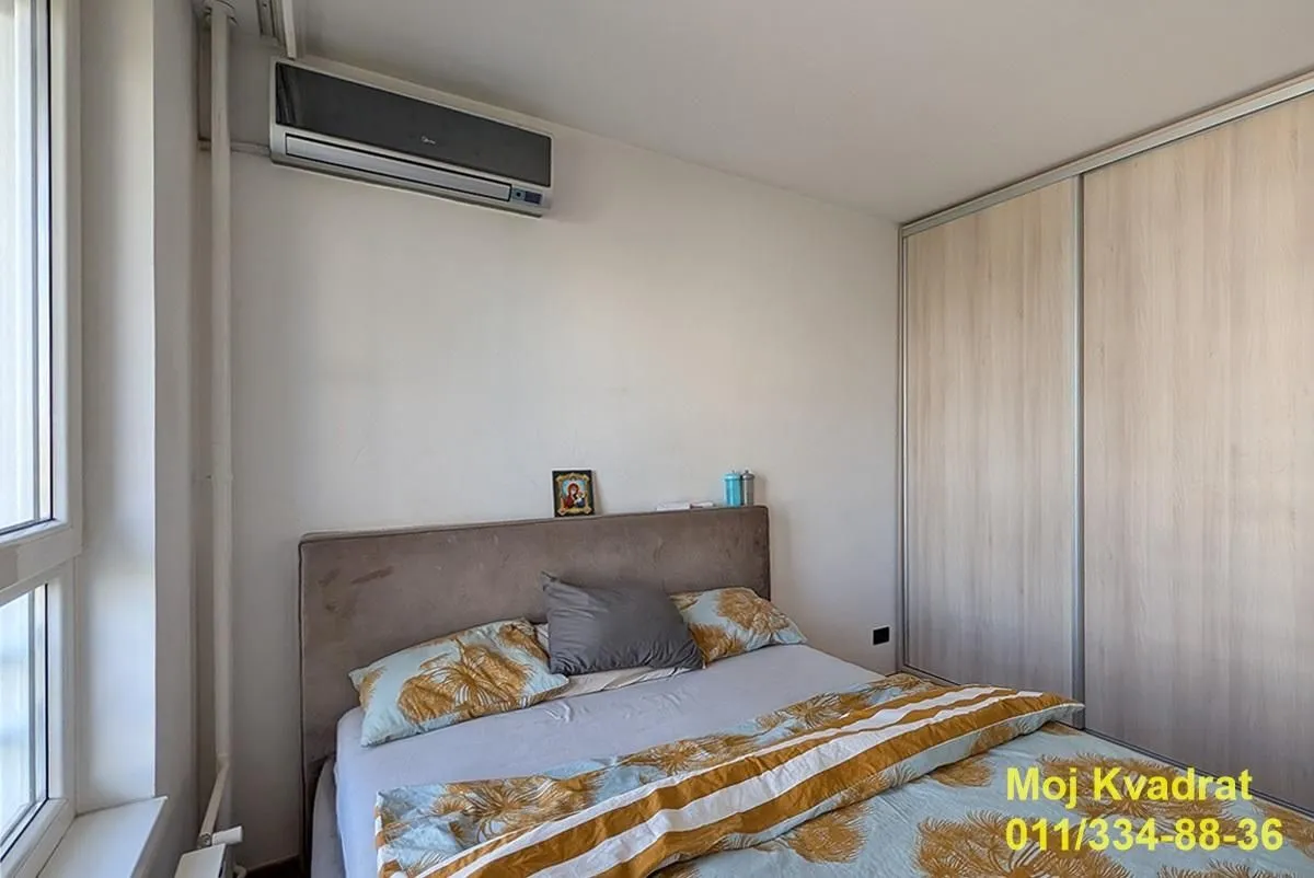 Spavaća soba sa bračnim krevetom, ugradnim ormanom i klima uređajem.