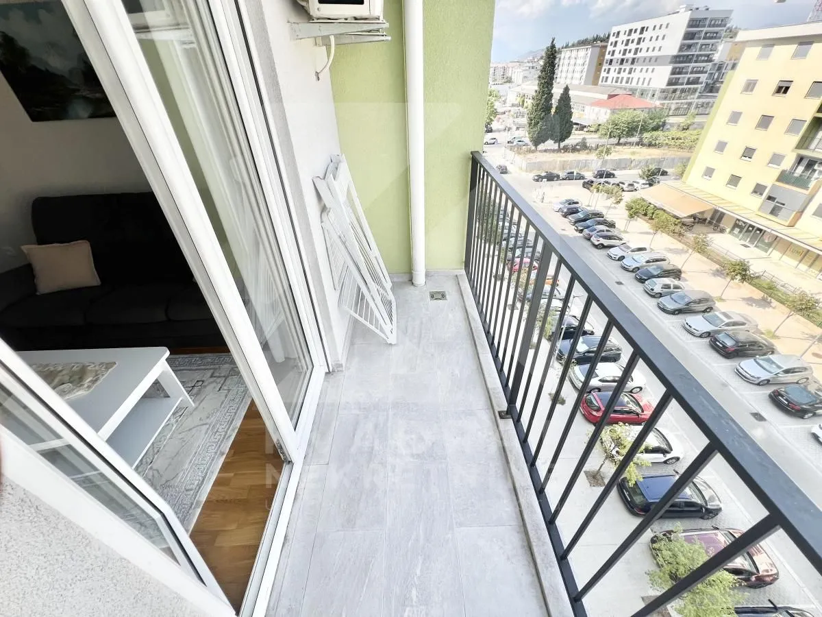 Balcony with a metal railing and a view of the street and parking.