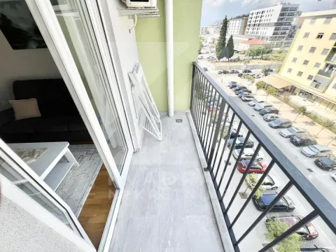 Balcony with a metal railing and a view of the street and parking. - image 10
