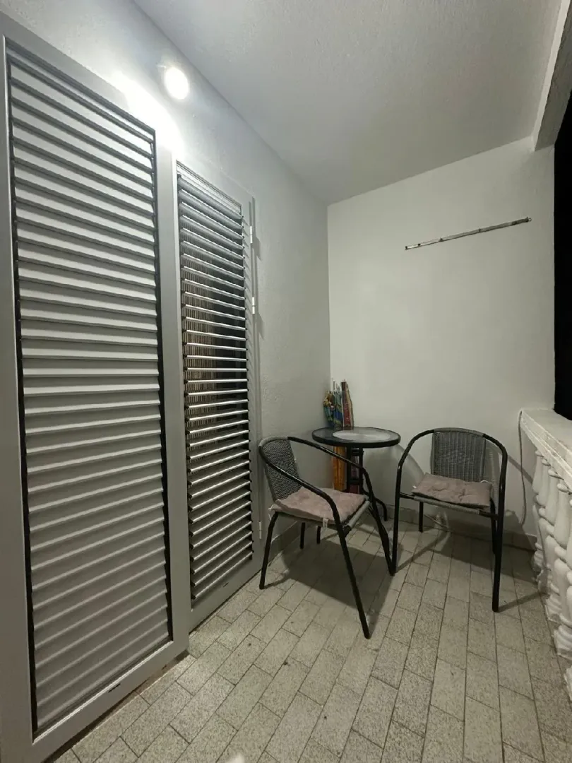 Small covered terrace with a table and two chairs.