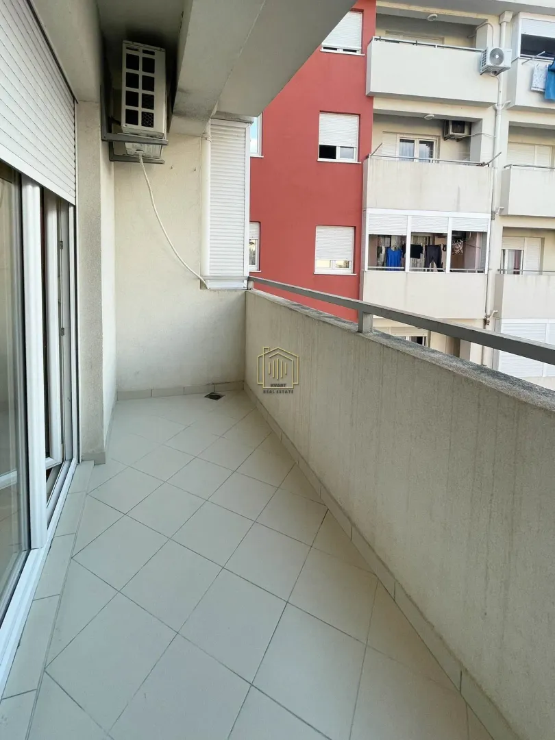 Natkriveni balkon sa popločanim podom i pogledom na susjednu zgradu.