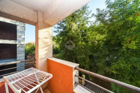 Natkriveni balkon sa pogledom na zeleno drveće. - image 5