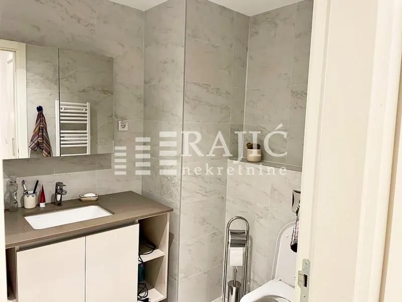 Modernly equipped bathroom with a washbasin and marble tiles.