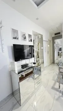 Dnevni boravak sa komodom, televizorom i ogledalima na zidu. - image 8