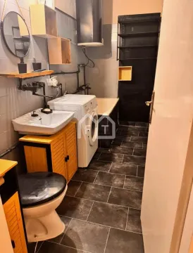 Small bathroom with a bathtub, washbasin, toilet, and washing machine. - image 14