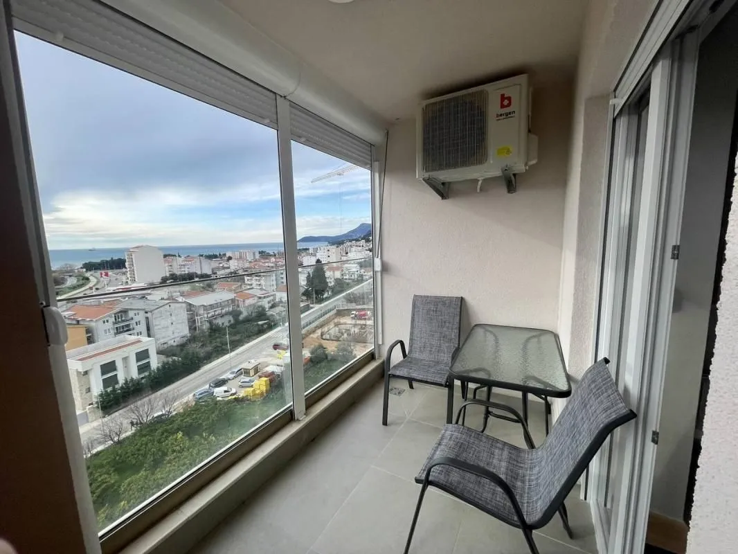 Glazed terrace with seating furniture and a view of the city and the sea.