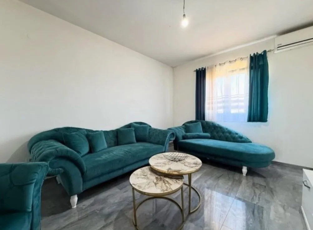 Living room with green sofas and round coffee tables.