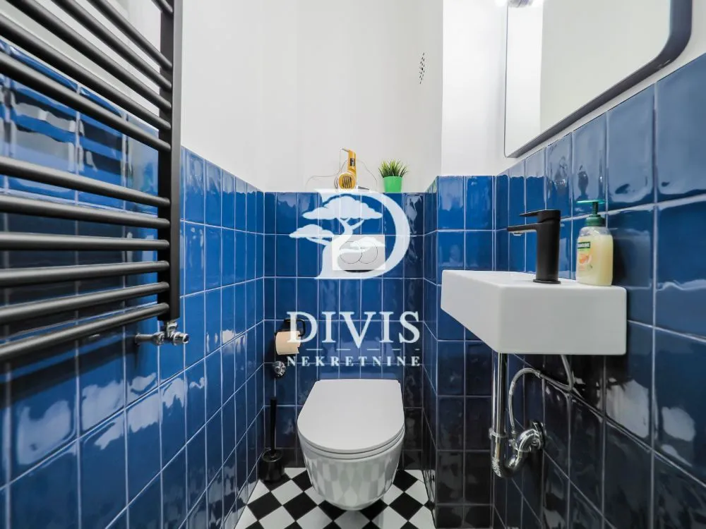 Smaller bathroom with blue tiles, sink and toilet.