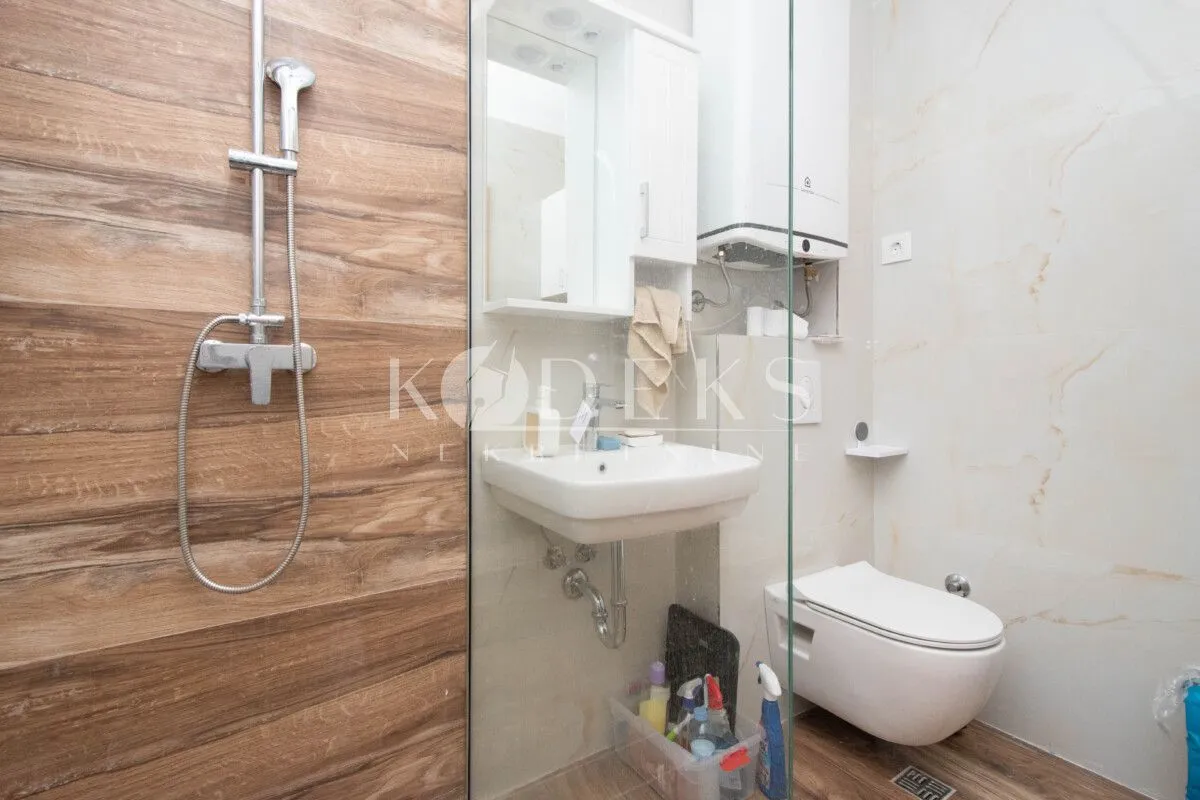 Compact bathroom equipped with a shower cabin, washbasin, and toilet.