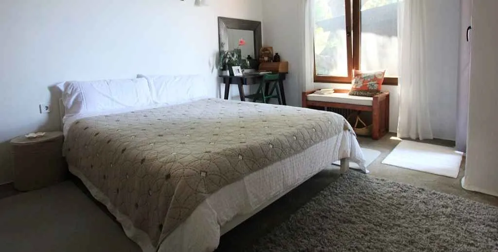 Svijetla spavaća soba sa velikim bračnim krevetom i radnim stolom.