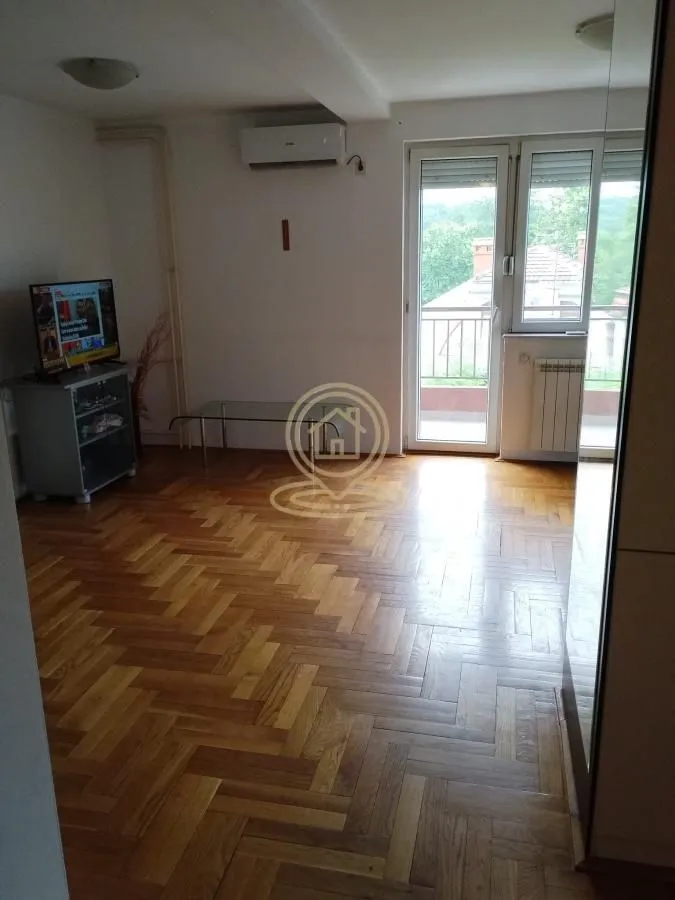 Dnevna soba sa parketom i izlazom na balkon.