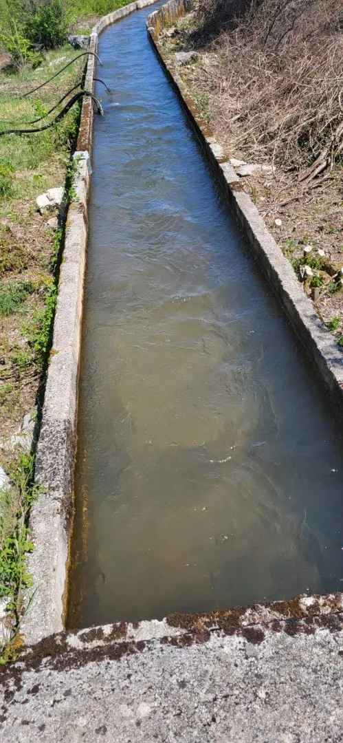 Betonski kanal sa vodom koji prolazi kroz dvorište.
