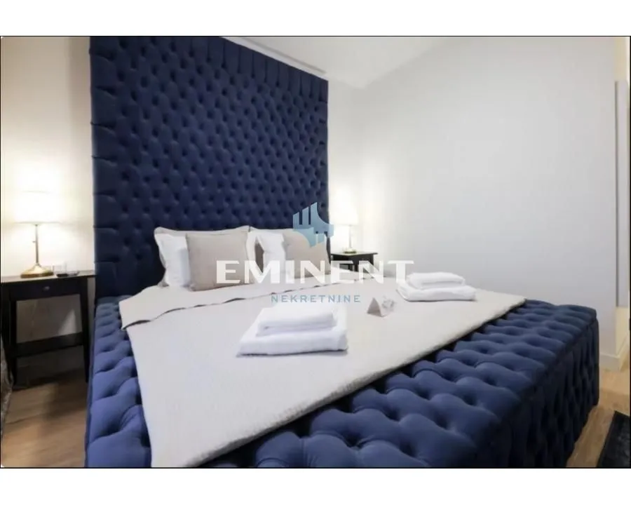 A bedroom with a large upholstered bed and bedside tables.