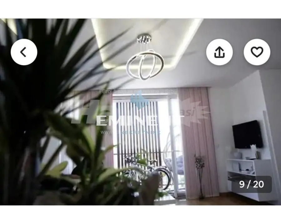 Dnevna soba sa modernim lusterom i izlazom na terasu.