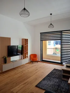 Spacious living room with wooden flooring, TV unit, and access to the terrace. - image 7
