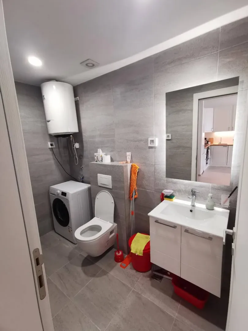 Moderne kupatilo sa tuš kabinom, umivaonikom, veš mašinom i bojlerom.