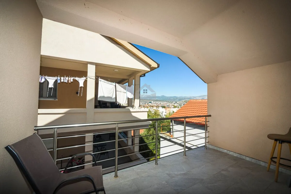Covered balcony with a metal railing and a view of the surroundings.