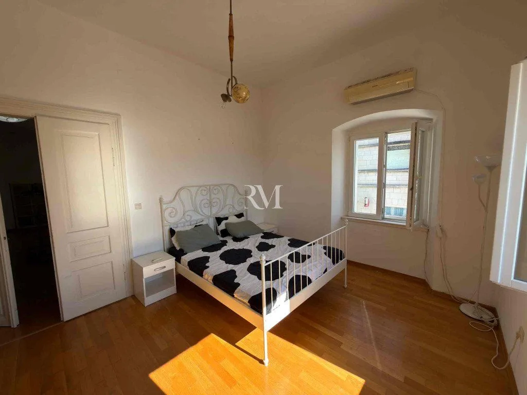 Bright bedroom with a double bed, wooden floor and a window.