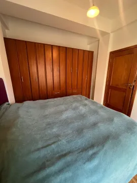 A bedroom with a large double bed, a wooden wardrobe, and a door. - image 5