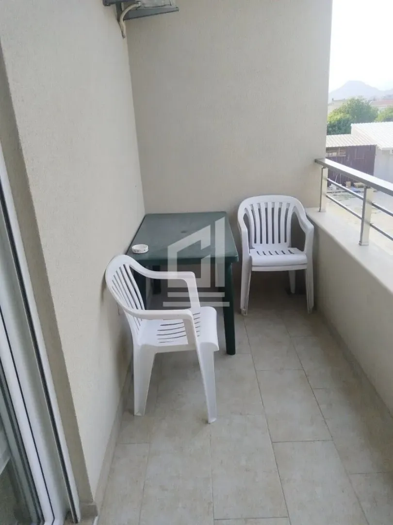 Natkriveni balkon sa plastičnim stolom i stolicama.