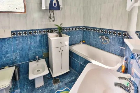 A bathroom with blue tiles, a bathtub, and a bidet. - image 19
