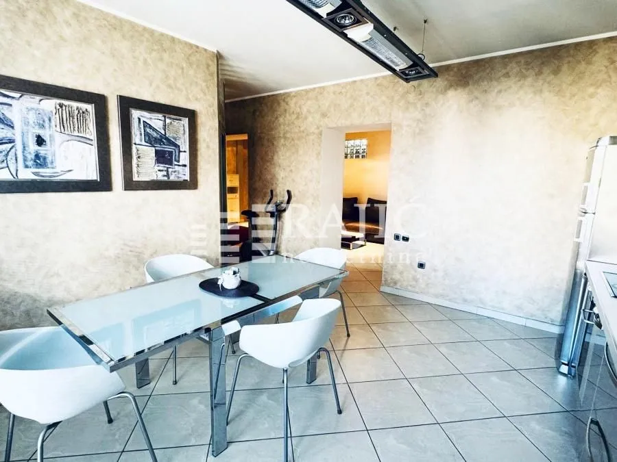 Dining area with a modern table and white chairs connected to the kitchen.