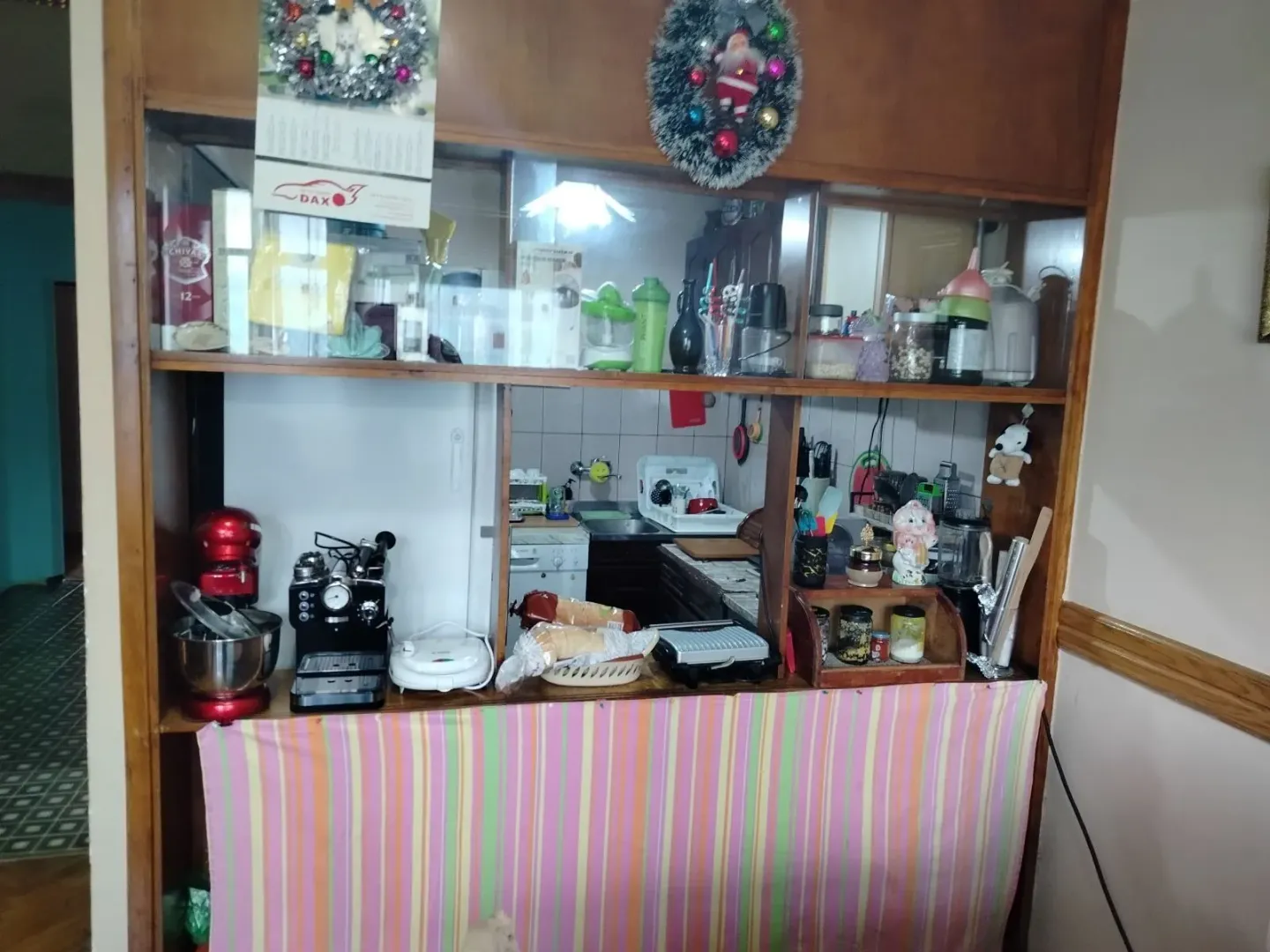 Pogled na kuhinju kroz drvenu pregradu sa aparatima i posuđem.