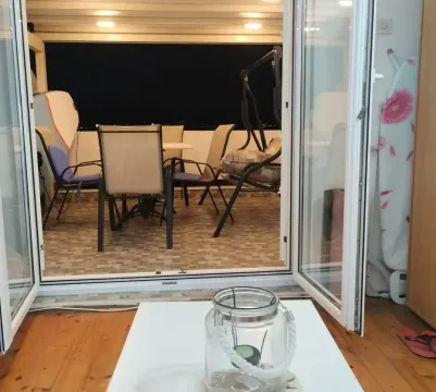 Pogled kroz otvorena balkonska vrata na terasu sa garniturom za sjedenje. - image 7