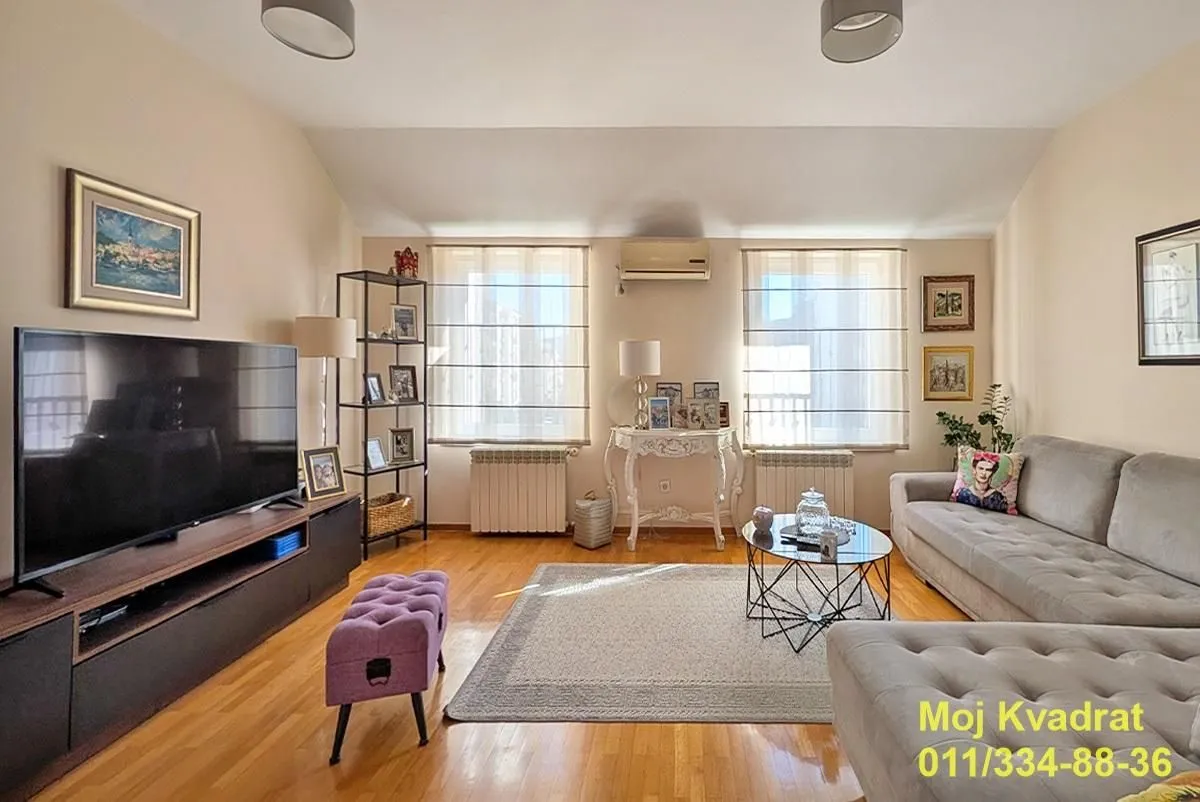 Furnished living room with sofa set, TV, and wooden flooring.