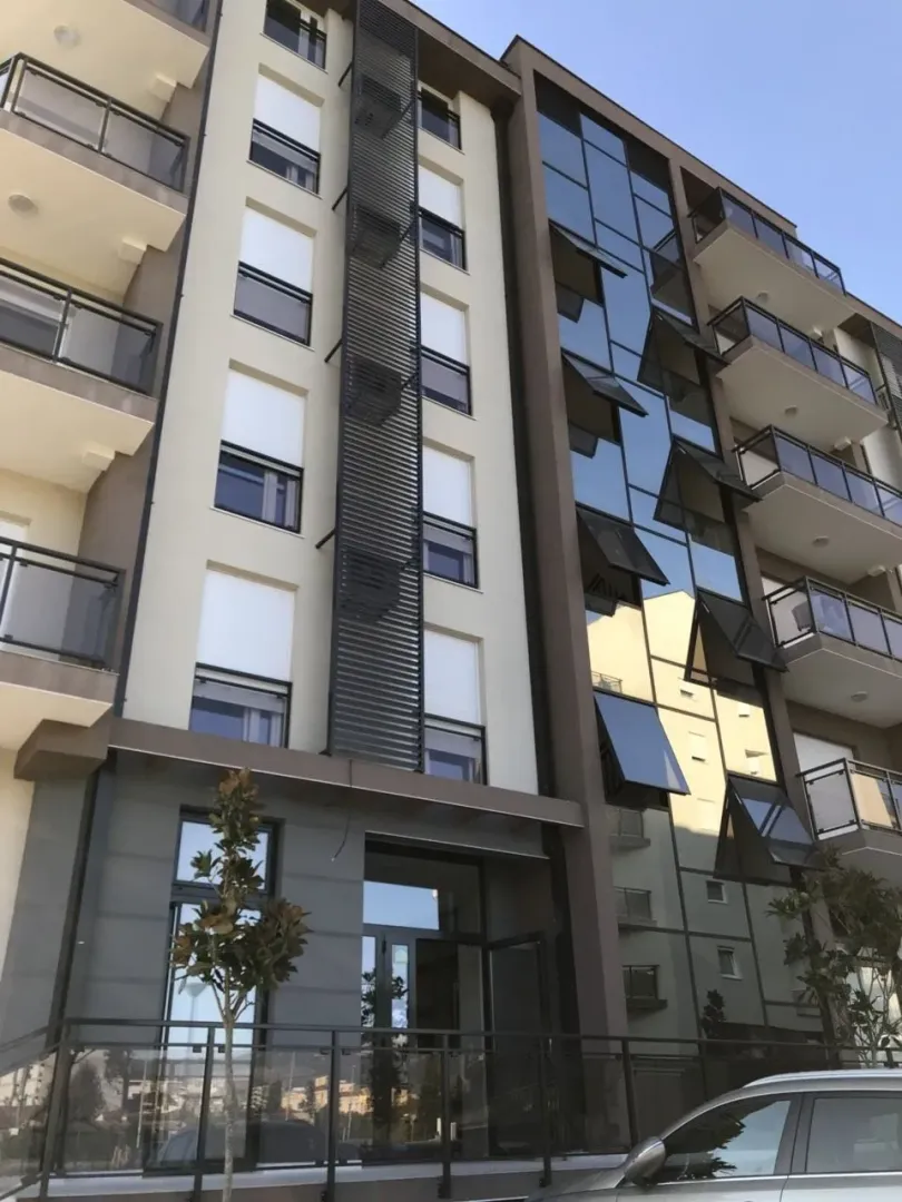 Modern facade of a residential building with glass features and balconies.