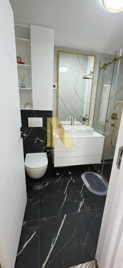 Moderno opremljeno kupatilo sa umivaonikom, WC šoljom i tuš kabinom.