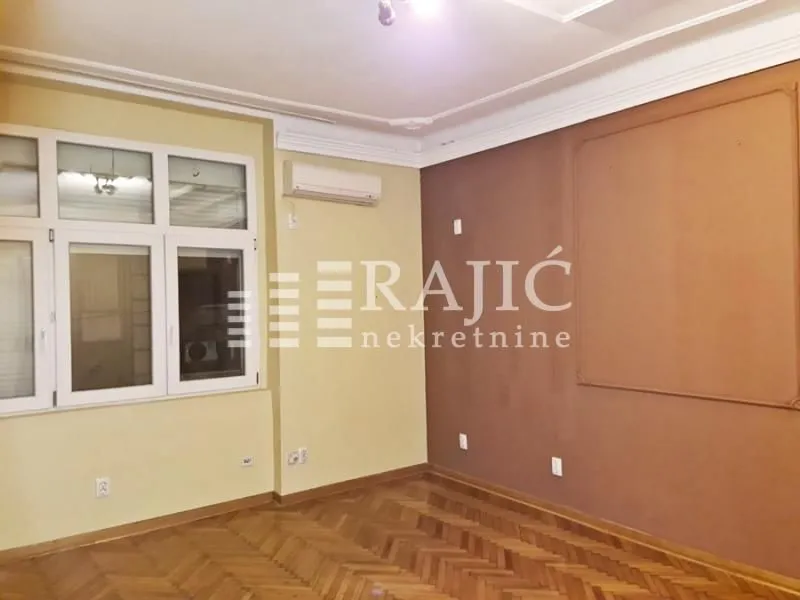Empty room with wooden parquet flooring and windows.