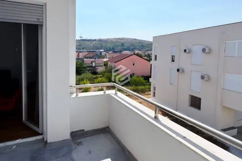 View from the balcony overlooking surrounding buildings and a hill. - image 2