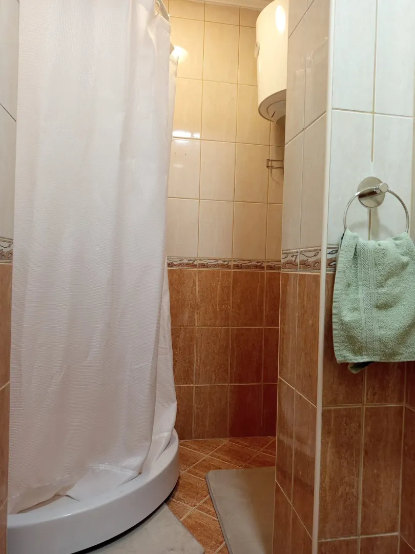 Bathroom with a shower cabin, tiles, and a water heater.