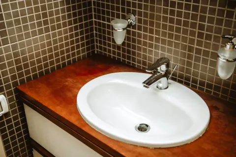 A bathroom sink with a faucet on a wooden countertop. - image 12