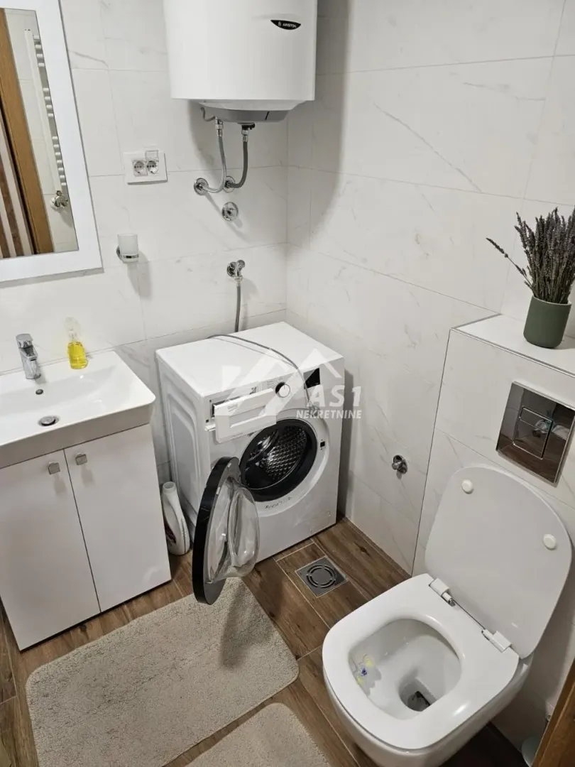 Kupatilo opremljeno umivaonikom, WC šoljom, veš mašinom i bojlerom.