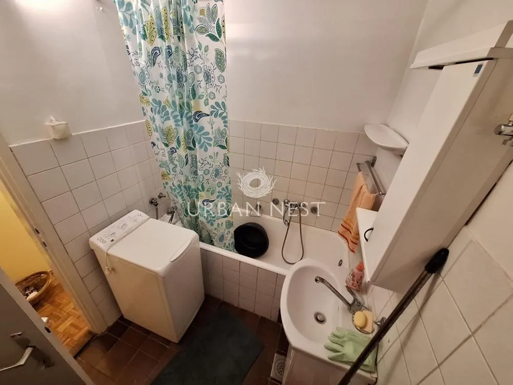 Small bathroom with a bathtub, washbasin, and washing machine.