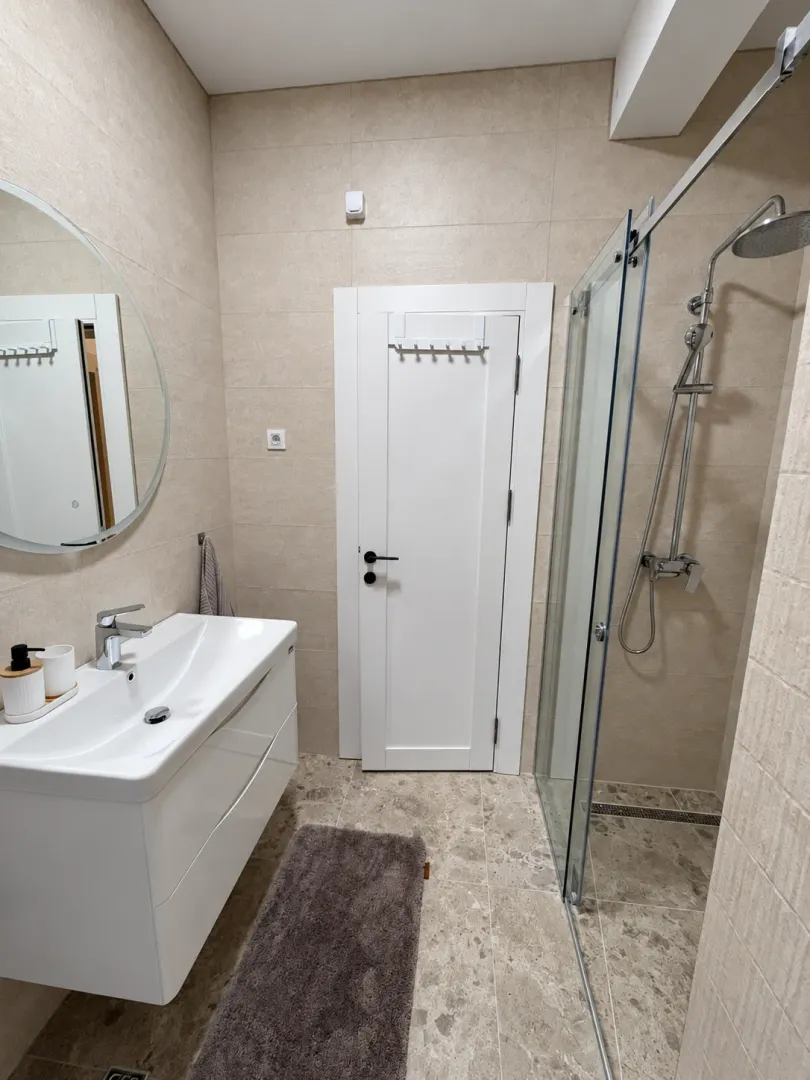 Modern bathroom equipped with a washbasin, mirror, and shower cabin.