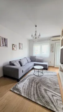 Living room with a sectional sofa, coffee table, and chandelier. - image 6