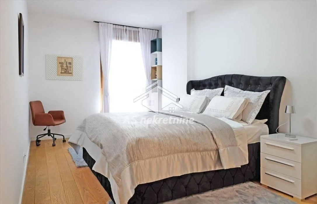 Spacious bedroom with a double bed, a desk, and a white nightstand.